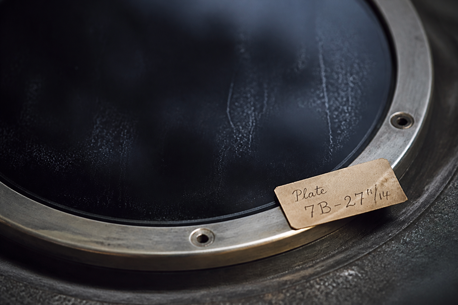 Cold metal chamber rim around a black glass observation plate with an exposure label